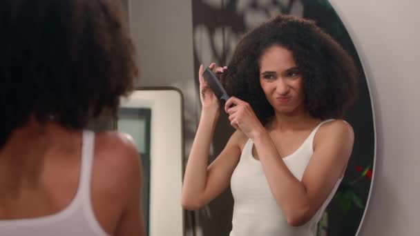 疲れ切った怒っている怒っているアフリカ系アメリカ人女性カールを組み合わせようとしている女性は 鏡の反射ガール女性の苦しみを見るヘアケアの問題に苦しんでいます トイレで毛をまっすぐつぶそう — ストック動画