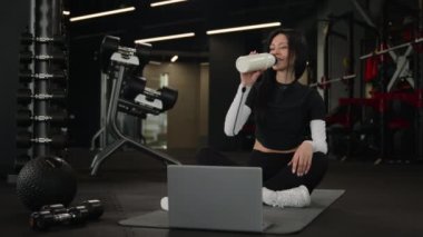 Genç güçlü spor fitness eğitmeni kadın eğitmen çevrimiçi sınıf yoga pilatesini laptopta egzersiz yaparken gülümseyen sporcu kadın spor salonunda iyi bir eğitim aldığını gösteriyor.