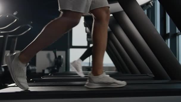 男子双腿紧跟在跑步机上跑的跑步机上跑的男子腿在健身俱乐部里跑的无法辨认的夫妇跑步者在体育馆里跑的女子和男子双脚跑的步法在赛马场上走的是步道有氧运动 — 图库视频影像