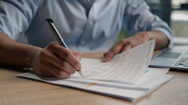 Sınav kağıtlarını ofis masasında bir bardak suyla bitiren erkek eli kapat. Kağıt notlar yazan iş adamı tanınmayan bir öğrenci. Belge metni, sigorta özeti.