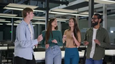 Grup çok ırklı arkadaşlar dostluk üniversite mezunları genç meslektaşlar dans eden iş kadınlarını kutluyor erkekler dans etmekten mutlu, alkışlayan hedef takım çalışması.