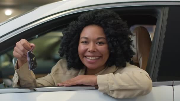 快乐的非洲裔美国女孩买新车的女顾客展示豪华轿车的钥匙开开开心心地微笑着做生意的女人在汽车经销店买汽车 — 图库视频影像