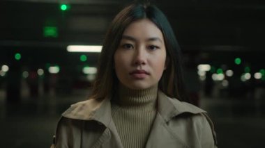 Kapalı portre ciddi bir Asyalı kadın sakin sakin sakin yüz ifadeleri araba parkında kameraya bakan genç Koreli kız Çinli Japon kadın sakin iş kadını vesikalık resmi