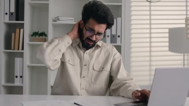 アラビアのインドのビジネスマンプログラマー オフィスデスクでラップトップを働く従業員 男性は首の痛みの腰痛の不快なコンピュータ仕事不健康な病気のビジネスマン 背部脊椎筋肉の健康管理 — ストック動画