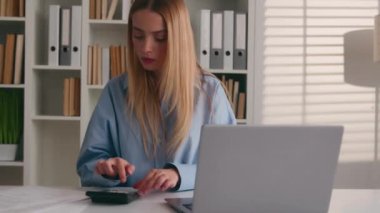 Hesap makinesi uygulaması kullanan beyaz bir kadın iş gelirleri proje giderlerini hesaplıyor. Yeni başlayan iş kadını muhasebeci kız için bütçe hesaplanıyor. Mali denetim yönetimini yönetiyor.