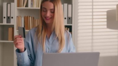 Kafkasyalı mutlu bir kadın banka kredi kartı laptopunu ev işlerinde online alışveriş ödemeleri için kullanıyor. Gülümseyen kız müşteri alıcısı bilgisayar E-bankacılık uygulama hizmeti ile satın aldı
