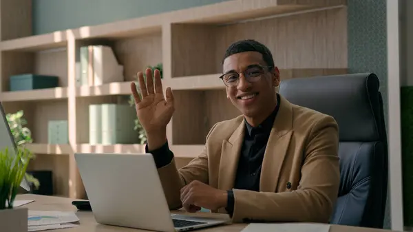 オフィスでラップトップコンピュータで働く幸せなアフリカ系アメリカ人の男 リモートジョブビジネスコマース プロのビジネスマン カメラ笑顔を振るハローフレンドリーなサインオンライン会議 — ストック写真