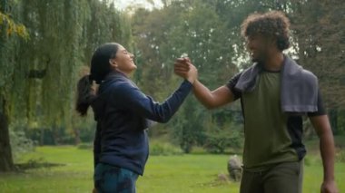 Hintli erkek ve kadın parkta spor yapıyor. Açık havada Arap fitness çifti şehirde spor egzersizleri sonrası beş arkadaşa koşuyor. Takım çalışması başarısı.
