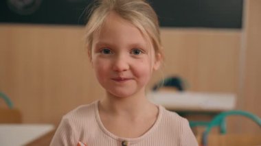 Portre yakın çekim küçük beyaz kız ilkokulda kameraya bakıyor sevimli 7ler çocuk liseli kız bebek öğrenci anaokulunda eğitim dersleri alıyor.