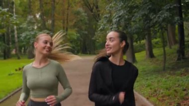Kafkas fitness kadınları, iki Avrupalı genç kız koşucular parkın dışında koşan genç bayan sporcular mutlu koşucular, sportif arkadaşlar, aktif koşu, kilo verme, şehirde sabah koşusu.