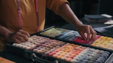 Tanınmayan erkek moda tasarımcısı terzi terzisi atölye atölyesinde kumaş koleksiyonu için yumuşacık iplik malzemelerini seçiyor erkek eller el işi için pembe kumaş örneği alıyor.