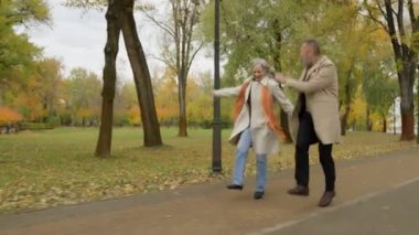 Kafkas kıdemli komik çift mutlu bir şekilde dışarı atlıyor neşeli evli eşler el ele tutuşuyor mutluluk duyguları dans ediyor olgun aile babası yaşlı kadın şehir parkında eğleniyor
