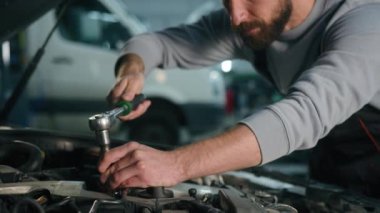 Otomobil istasyonunda çalışan beyaz tenli profesyonel oto tamircisi erkek motor tamircisi garajda anahtarı anahtarla bozuk araba tamir ediyor.