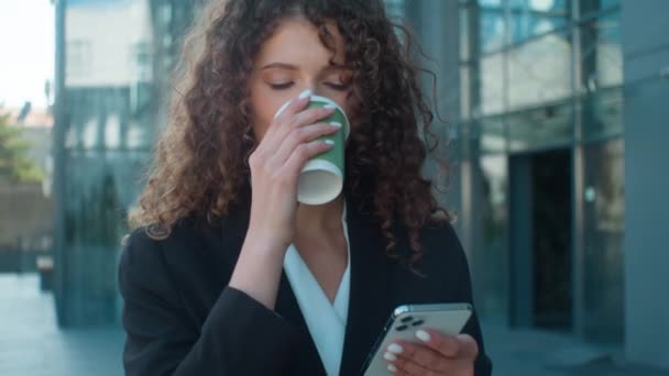 コーヒー屋外でコーヒーを飲む街路を歩く白人の若い女性のビジネスマンは 驚くべきビジネスガールショックの失敗を飲んで携帯電話のチョークで衝撃的なニュースを読んで混乱しました — ストック動画