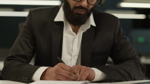 印度男人阿拉伯男人企业家商业男生实习生导师顾问商人在笔记本上写笔记听耳机在线课堂教学视频电话在办公室 — 图库视频影像