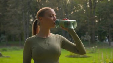 Kafkas kız fitness kadın koşucu kadın parkta şişe ile içme suyu alışkanlık ferahlatıcı vücut suyu gülümseyen sporcu kadın yeşil elma sağlıklı vitaminler spor beslenme zayıflaması