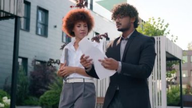 Hintli Arap erkek işadamı, elinde belgeler olan işadamı. Şirketler, şehir merkezinde çok ırklı iş adamlarıyla yürüyen Afrikalı Amerikalı kadın iş kadınıyla sonuç planlarını tartışıyor.