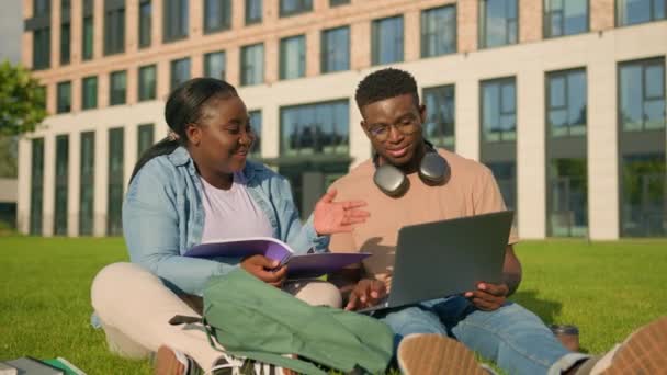 アフリカ系アメリカ人の遺伝子Zの学生ガール女性は オンラインタスクを持つ男を助け 宿題の友人と一緒にプロジェクトコンピュータ学習大学の学生をラップトップで勉強する — ストック動画