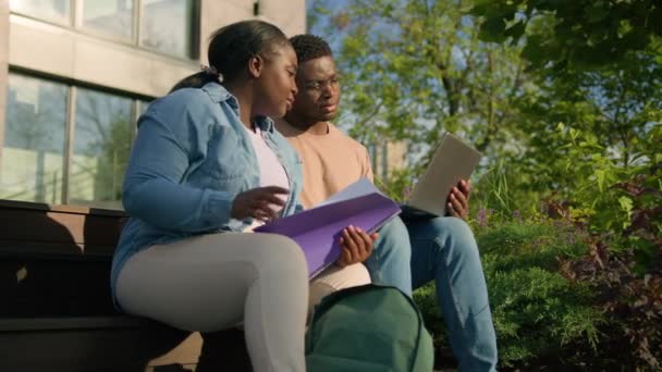 两个非洲学生的高中女生在城外的大学校园里坐在长椅上讨论问题一起准备大学考试或考试用笔记本电脑进行教育研究 — 图库视频影像