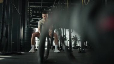 Beyazlı fitness adamı spor salonunda halatla çapraz antrenman yapıyor güçlü kaslı sporcu erkek vücut geliştirme sporcusu aktif kardiyo egzersiz dayanıklılığı spor kulübünde vücut geliştirme egzersizi yapıyor.