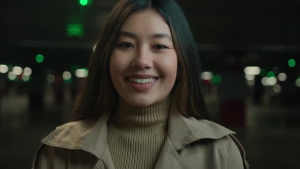 亚洲漂亮女孩美丽的华裔韩裔女孩快乐快乐的商务女士笑容可亲的日本女车主在黑暗的停车场看着相机 牙齿笑得很好 — 图库视频影像