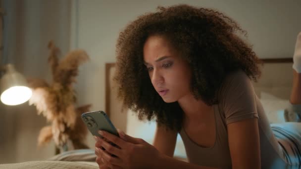 Upsetショック悲しいアフリカ系アメリカ人女性失望した民族女性は携帯電話のクラッシュモバイルエラーの間違いメッセージは スマートフォン損失の故障悪いニュースでベッドの夜の家で女性をイライラさせました — ストック動画