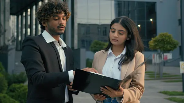 Indian male man businessman ceo boss leader consulting Arabian woman female businesswoman intern explaining insurance business contract negotiate discuss agreement papers help documents advice at city