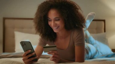 Mutlu Afro-Amerikalı 20 'li yaşlarda bir kız internet siparişi için cep telefonu ödemesi yapıyor. Başarılı bir ödeme, öpme kartı alışverişi, akıllı telefon dijital servis e-ticareti, internet bankacılığı.
