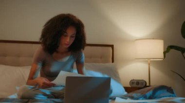 Evde geç saatlere kadar çalışan meşgul Afro-Amerikan kız öğrenci internetten bilgisayarla incelemeye hazırlan. Kadın iş kadını, evrak işleri, yurt içi elektrik faturalarını kontrol et.