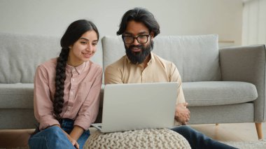 Çok ırklı bir çift olan Arap erkek ve Hintli aile fertleri ev sahibi çift ev sahibi karı koca sevgili dizüstü bilgisayarda film izleyen sevgili akıllı televizyon keyfi, gülümseme, konuşma videosu, gülümseme, gülücük.