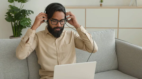 与笔记本电脑一起上网工作的阿拉伯裔商人疲惫不堪 疲惫不堪的印度人精疲力竭的生意人坐在手机里听着冰冷的音乐 闭着眼睛 无忧无虑地在家里放松一下 — 图库照片