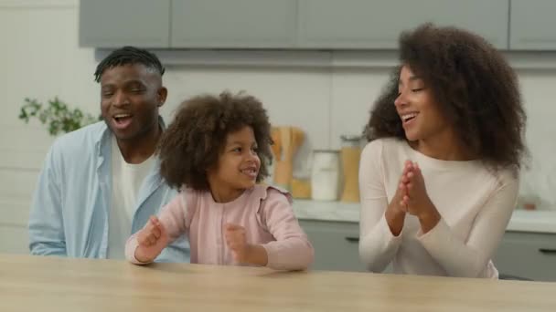 无忧无虑的非洲裔美国人家庭孩子快乐的父母和可爱的小女孩在厨房里一起跳着音乐快乐地跳舞有趣的妈妈爸爸和女儿在一起跳舞 — 图库视频影像