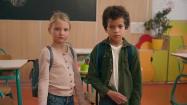 Ciddi bir şekilde kendinden emin Afrikalı ve Kafkas kökenli küçük okul çocukları çok ırklı kız ve erkek çocuklar okul çocukları ilkokul öğrencileri el ele tutuşarak suç işlediler.