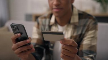 Tanınmayan Afrikalı Amerikalı adamın elinde plastik banka kartı var. Akıllı telefon. Sanal para nakitsiz finansman.