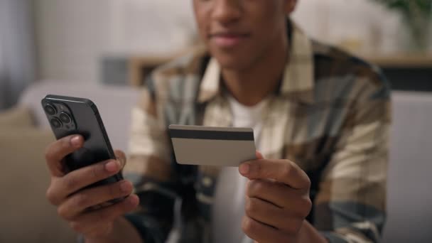 認識できないアフリカ系アメリカ人男性ホールドプラスチック銀行クレジットカードスマートフォン仮想マネーキャッシュレスファイナンストランザクション支払いオンラインインターネット決済バンキング携帯電話ショッピング人購入家 — ストック動画