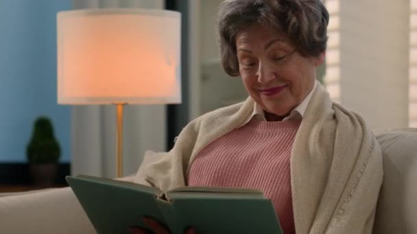 ハッピーインスピレーションを受けたコーカサス古い女性シニア成熟した女性リラックスした落ち着いた年配の女性 引退した中年のおばあちゃん年金おばあちゃんは 家庭のソファー読書本で一人で読む新しい文学リラックスをお楽しみください — ストック動画
