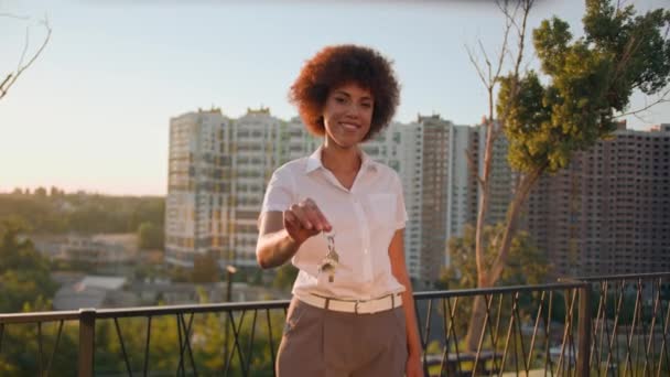 ハッピー笑顔成功したアフリカ系アメリカ人女性 街の建物の高層ビル近くのアフリカ人女性 宿泊施設を示すポーズ 女性不動産の束 新しいフラットホームアパートの販売を購入 — ストック動画
