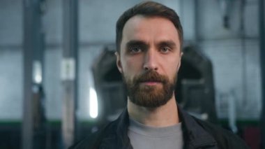 İş üniformalı yetişkin beyaz adam profesyonel araba tamircisi kameraya bakan ciddi yüzlü, kendine güvenen küçük araba tamircisi araba tamircisi.