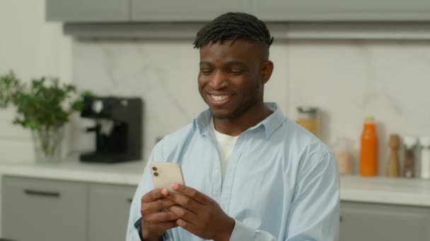 Ευτυχισμένος Χαμογελαστός Αφροαμερικάνος Που Παίζει Κινητό Τηλέφωνο Στο Σπίτι Κουζίνα — Αρχείο Βίντεο