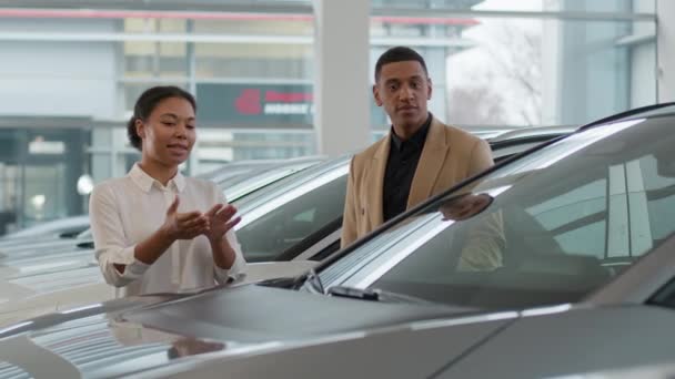 销售经理妇女汽车代理人帮助非洲裔美国人客户商人在展示厅选择新的豪华汽车 并在汽车经销店谈论租车服务 — 图库视频影像
