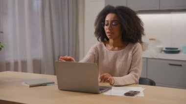 Masada dizüstü bilgisayarı yazan Afrikalı Amerikalı kadın girişimci ev mutfağı kadın serbest iş kadını bilgisayar işini bitirdi. Gözlüklü gülüşünü çıkardı.