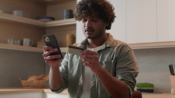 ホームキッチンでインスタントモバイル決済を使用して携帯電話とクレジットカードを持つハッピーアラビア人男性男性男性男性カスタマー買い手 オンライン購入 スマートフォンショッピング食品配信Eバンキングアプリ — ストック動画
