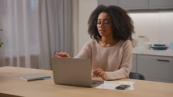 アフリカ系アメリカ人女性起業家 テーブルでラップトップをタイプする起業家 ホームキッチンからオンライン起業ビジネスプロジェクト 女性フリーランスのビジネスマン メガネを取り除くコンピュータ作業を終了 夢の笑顔 — ストック動画