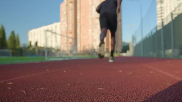 スタジアムの低スタート位置のバックビューランナーは 男性スポーツマンジョギングの準備ができて アフリカの未知のスポーツマンアウトドアをジョギングマラソンを起動します 朝のジョギング健康的なアクティブライフスタイル — ストック動画