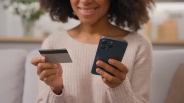 Tanımlanamayan afro-amerikan kadın gülümsemesi cep telefonlu telefon siparişi dükkanı kredi kartı akıllı telefon alışverişi internet üzerinden para transferi e-ticareti.
