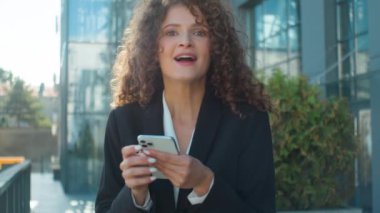 Kafkasyalı iş kadını umut ediyor mutlu mutlu mutlu cep telefonu çevrimiçi bahis zaferi kutluyor şaşırmış iş kadını şehir güneşinde öpücükler akıllı telefon başarısı iyi haber