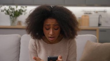 Evde cep telefonundan kötü haberler okuyan Afro-Amerikalı genç bir kadın üzgün mutsuz bir kızı kaybetti. Mesajı reddettiği için endişeli. Akıllı telefon hatası.