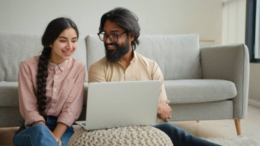 Çok ırklı bir çift olan Arap erkek ve Hintli aile fertleri ev sahibi çift ev sahibi karı koca sevgili dizüstü bilgisayarda film izleyen sevgili akıllı televizyon keyfi, gülümseme, konuşma videosu, gülümseme, gülücük.