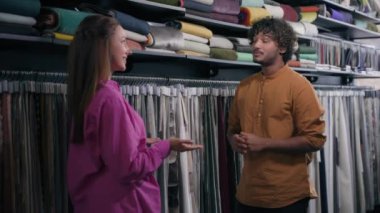 Kumaş mağazası perakende satış asistanı müşterisi mutlu Arap Hindistanlı adamla konuşuyor ve gülümseyen beyaz kadın beş çok ırklı iş ortağı tekstil dükkanında anlaşma satışı yapıyor.