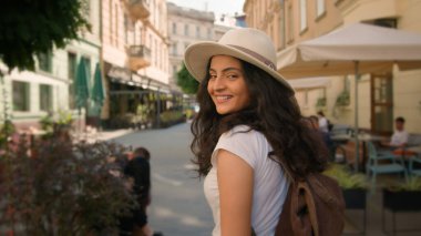 Neşeli, neşeli, güler yüzlü, Hintli, şık, Arap kadın, bayan turist, geri dönüyor. Dönüşte kamera görüntüsü, sokak gezileri, hafta sonları şehir seyahatleri.